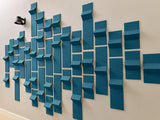 Teal dimensional tiles arranged in a staggered pattern on a beige wall with varying depths and angles.