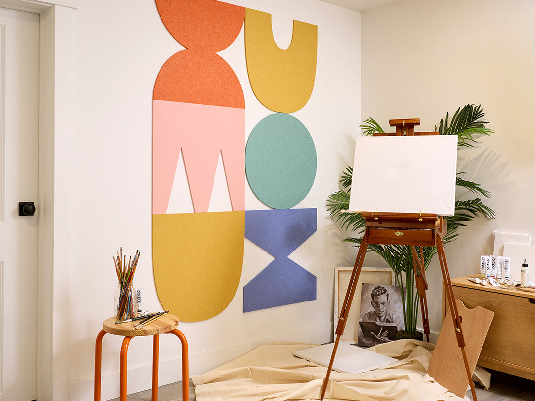 Colorful abstract acoustic wall art in a room with an easel and plants