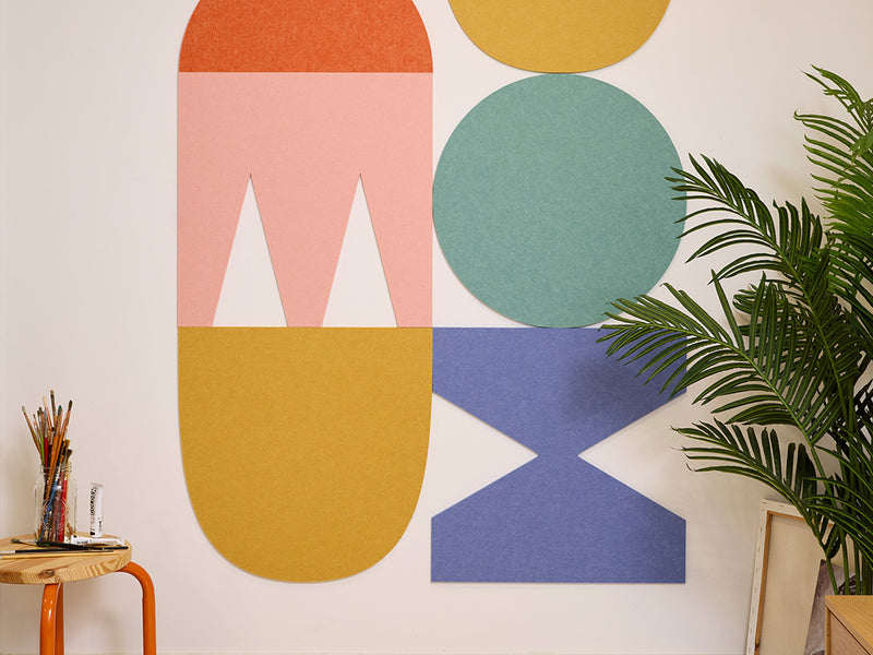 Colorful geometric wall art with a plant on a white wall