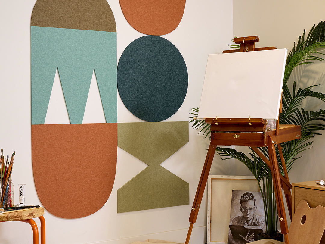 Easel with a blank canvas against a wall with abstract geometric shapes
