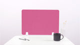 Pink desk divider with wavy cutout design, standing on white desk with pens, mug, and vase.