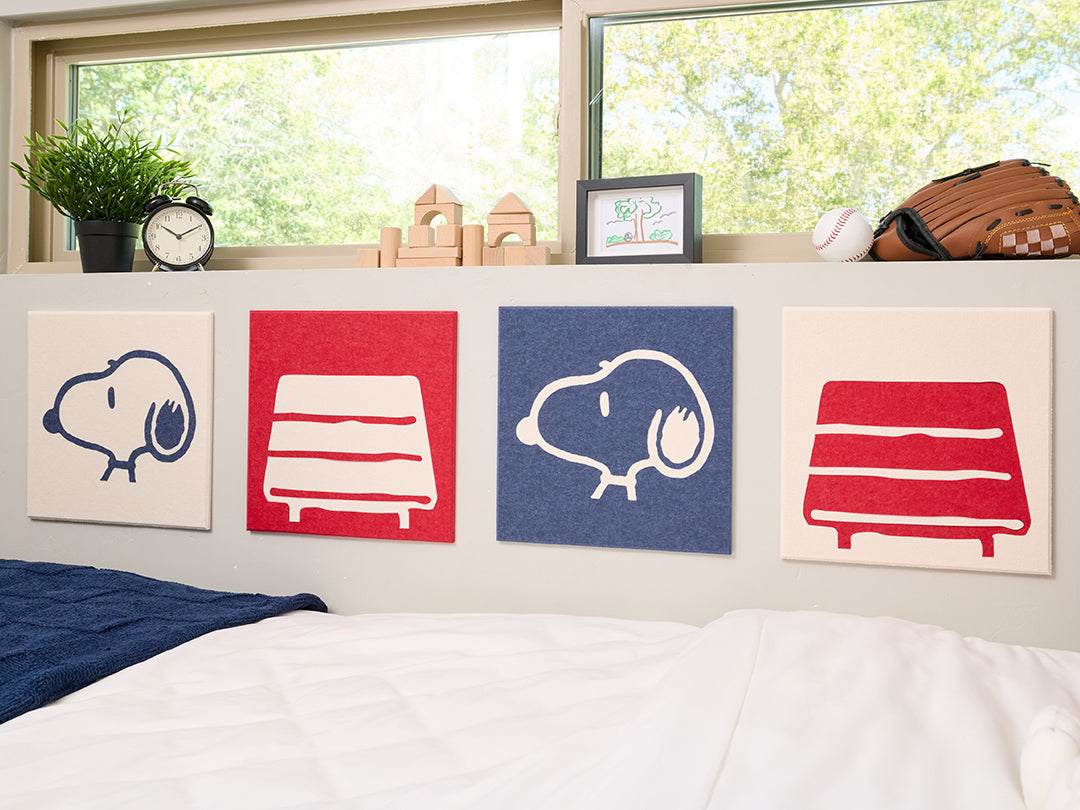 Bedroom with Snoopy plush toy and decorative pillows on a bed, featuring Snoopy illustrations on the wall.