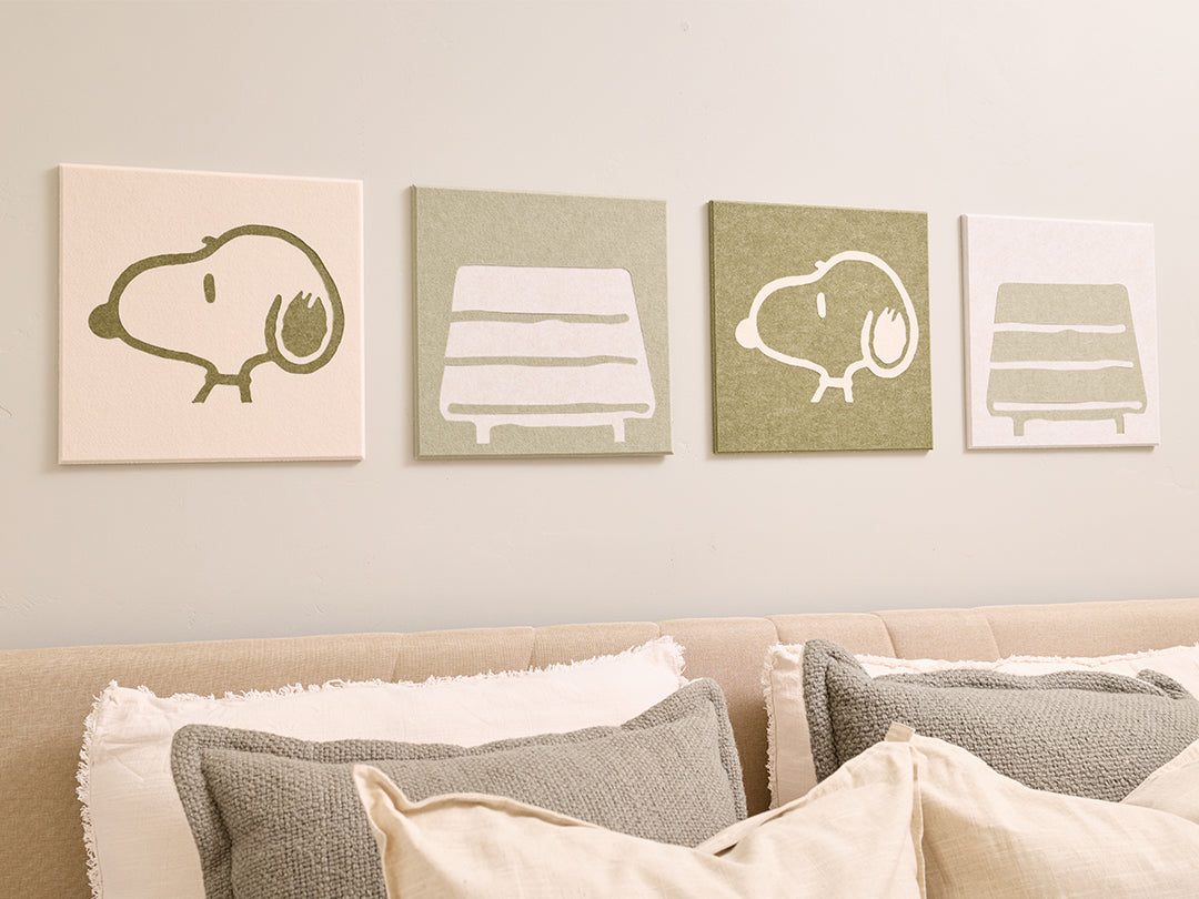 Bedroom with Snoopy plush toy and decorative pillows on a bed, featuring Snoopy illustrations on the wall.