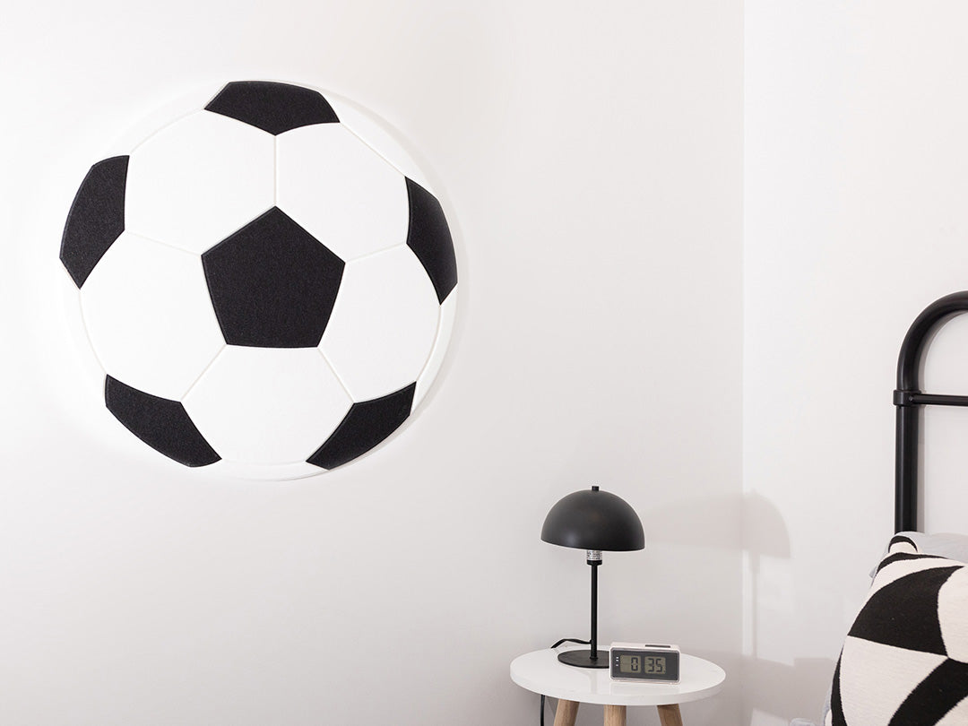 Black and white soccer ball wall decoration in a room with a lamp and pillow.