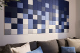 Horizontal wall art with blue, gray, and white checkered squares hung above a gray sofa.