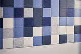 Mosaic tile arrangement with horizontal rows of blue, navy, gray, and cream colored square tiles with textured surfaces.