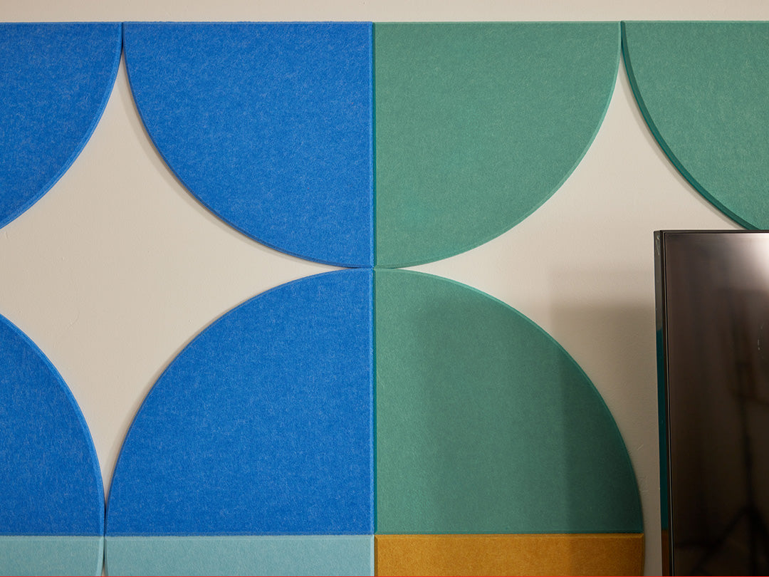 Geometric pattern of blue and green circles on a wall with a television in the corner.