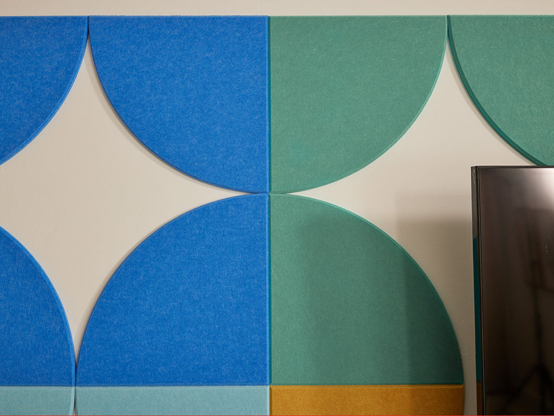 Geometric pattern of blue and green circles on a wall with a television in the corner.