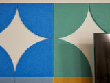 Felt Right wall art using quarter circles to make a diamond like star in shades of blue and green.