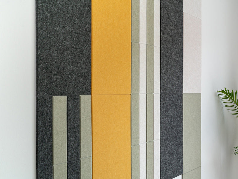 Felt Right wall art design in shades of green, yellow, white, and black on a white wall 