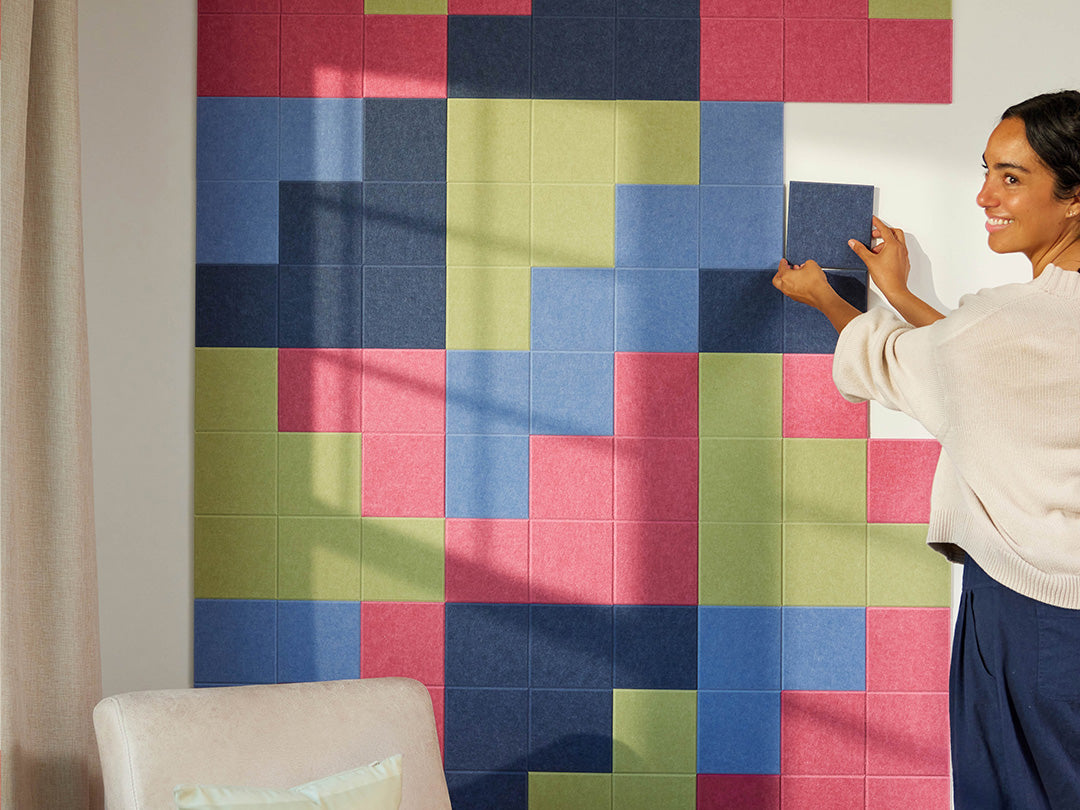 Woman arranging colorful square tiles on a wall