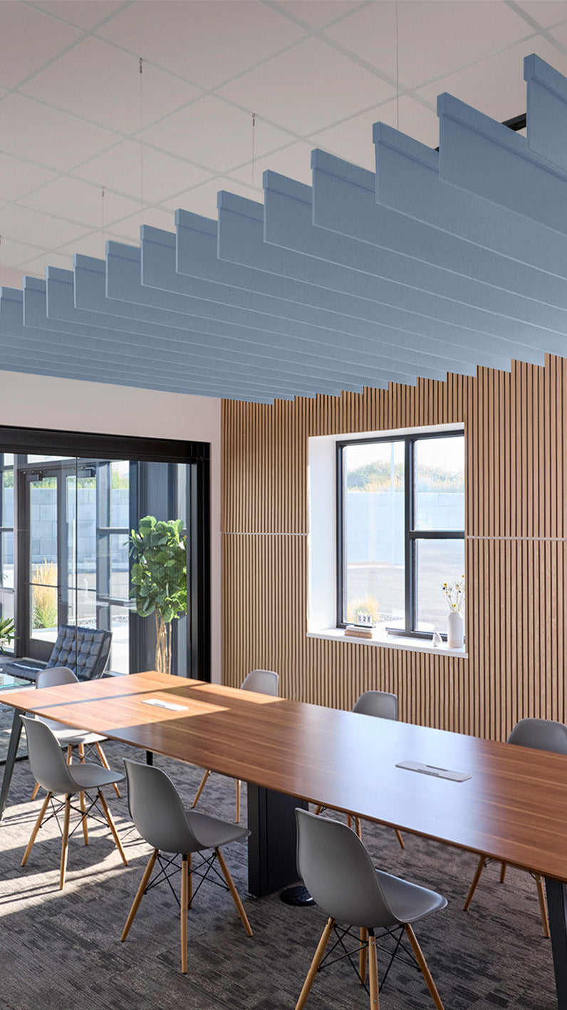 Blue straight acoustic blade baffles suspended from ceiling above conference table in office space.
