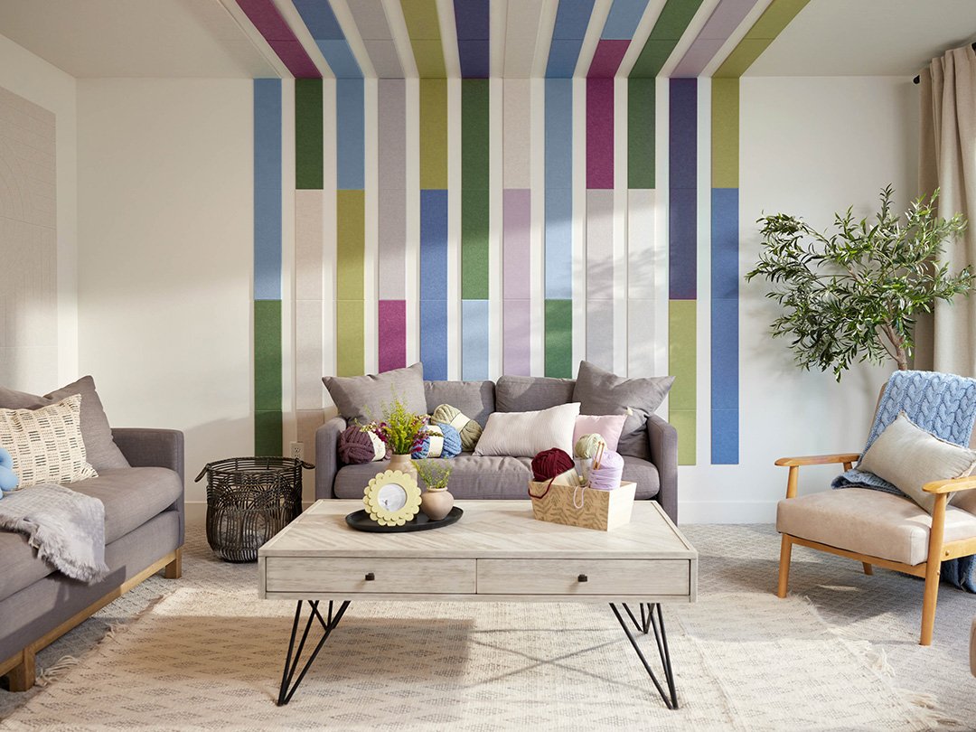 Felt right wall art design in shades of blue, green, purple, and cream felt tiles in a geometric shape lining the wall and the ceiling in a living room with a couch and a coffee table.