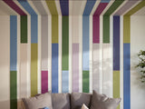 Felt right wall art design in shades of blue, green, purple, and cream felt tiles in a geometric shape lining the wall and the ceiling in a living room with a couch.