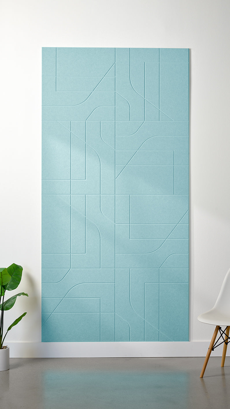 Baby blue Felt Right 4’ x 8’ PET felt panel with intersecting lines similar to a transit system map engraved into the material against a white wall. A plant and chair are in the foreground.
