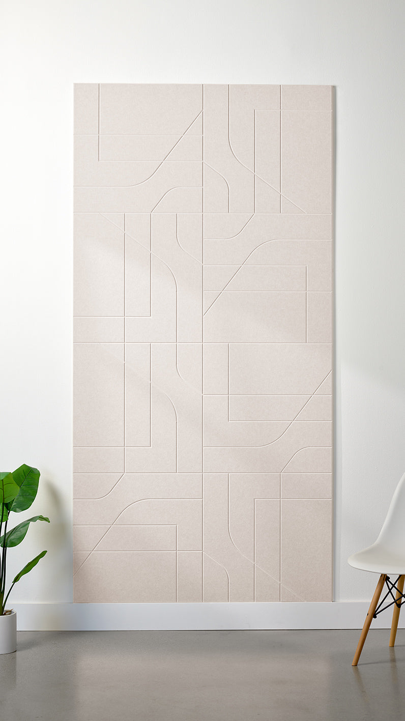 Heathered beige Felt Right 4’ x 8’ PET felt panel with intersecting lines similar to a transit system map engraved into the material against a white wall. A plant and chair are in the foreground.