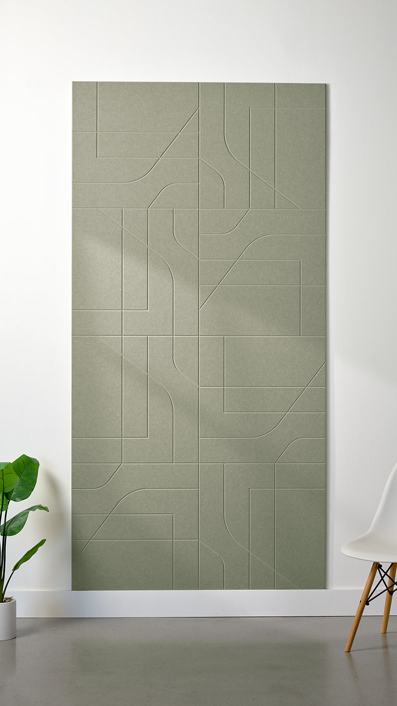 Sage green Felt Right 4’ x 8’ PET felt panel with intersecting lines similar to a transit system map engraved into the material against a white wall. A plant and chair are in the foreground.