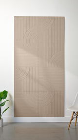 Camel Felt Right 4’ x 8’ PET felt panel with straight and circular lines engraved into the material against a white wall. A plant and chair are in the foreground.