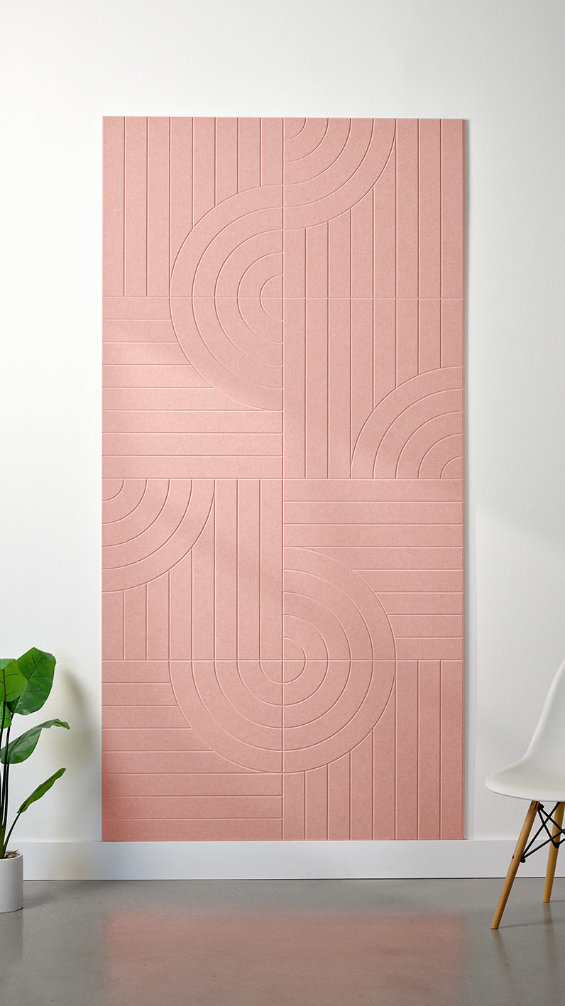 Light pink Felt Right 4’ x 8’ PET felt panel with straight and circular lines engraved into the material against a white wall. A plant and chair are in the foreground.