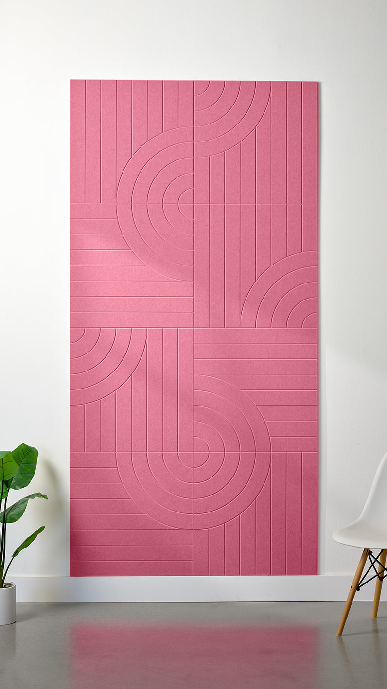 Hot pink Felt Right 4’ x 8’ PET felt panel with straight and circular lines engraved into the material against a white wall. A plant and chair are in the foreground.