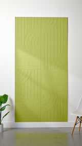 Bright green Felt Right 4’ x 8’ PET felt panel with straight and circular lines engraved into the material against a white wall. A plant and chair are in the foreground.
