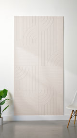 Heathered beige Felt Right 4’ x 8’ PET felt panel with straight and circular lines engraved into the material against a white wall. A plant and chair are in the foreground.