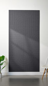 Grey Felt Right 4’ x 8’ PET felt panel with straight and circular lines engraved into the material against a white wall. A plant and chair are in the foreground.