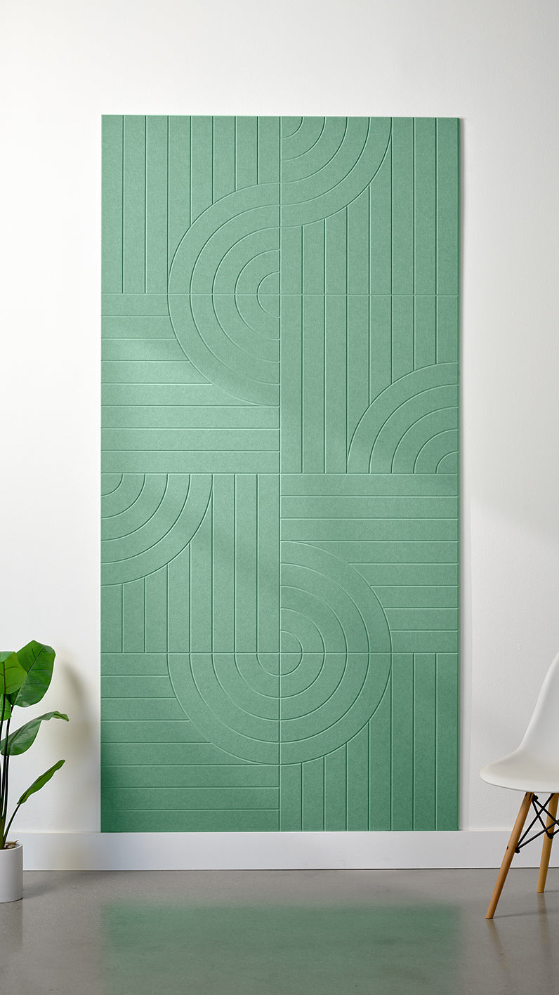 Mint green Felt Right 4’ x 8’ PET felt panel with straight and circular lines engraved into the material against a white wall. A plant and chair are in the foreground.