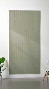 Sage green Felt Right 4’ x 8’ PET felt panel with straight and circular lines engraved into the material against a white wall. A plant and chair are in the foreground.