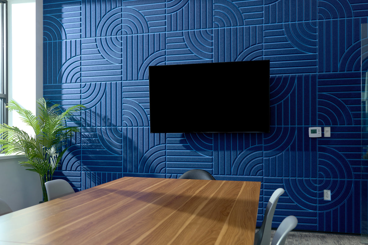 Modern office space with blue textured acoustic wall panels and a wooden table.