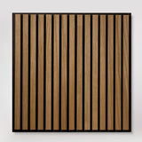 A square wooden slat panel with vertical oak-toned wood strips set in a black frame, shown against a plain light background.