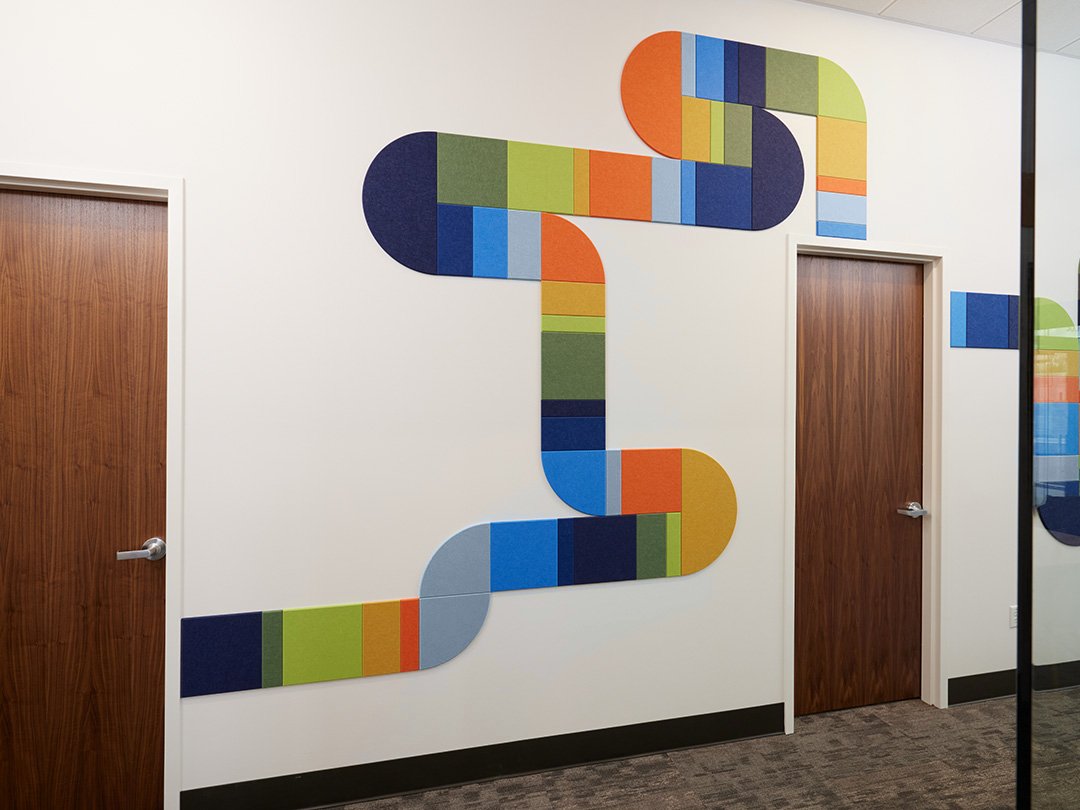 felt right wall art design in multicolors creating a pipe-like design going down a hallway with doors 