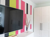 Pink and green wall art behind Tv