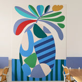 Large abstract floral wall art installed on a white wall in a modern office or meeting room setting, with blue paneling, chairs, and a wooden table visible at the bottom.