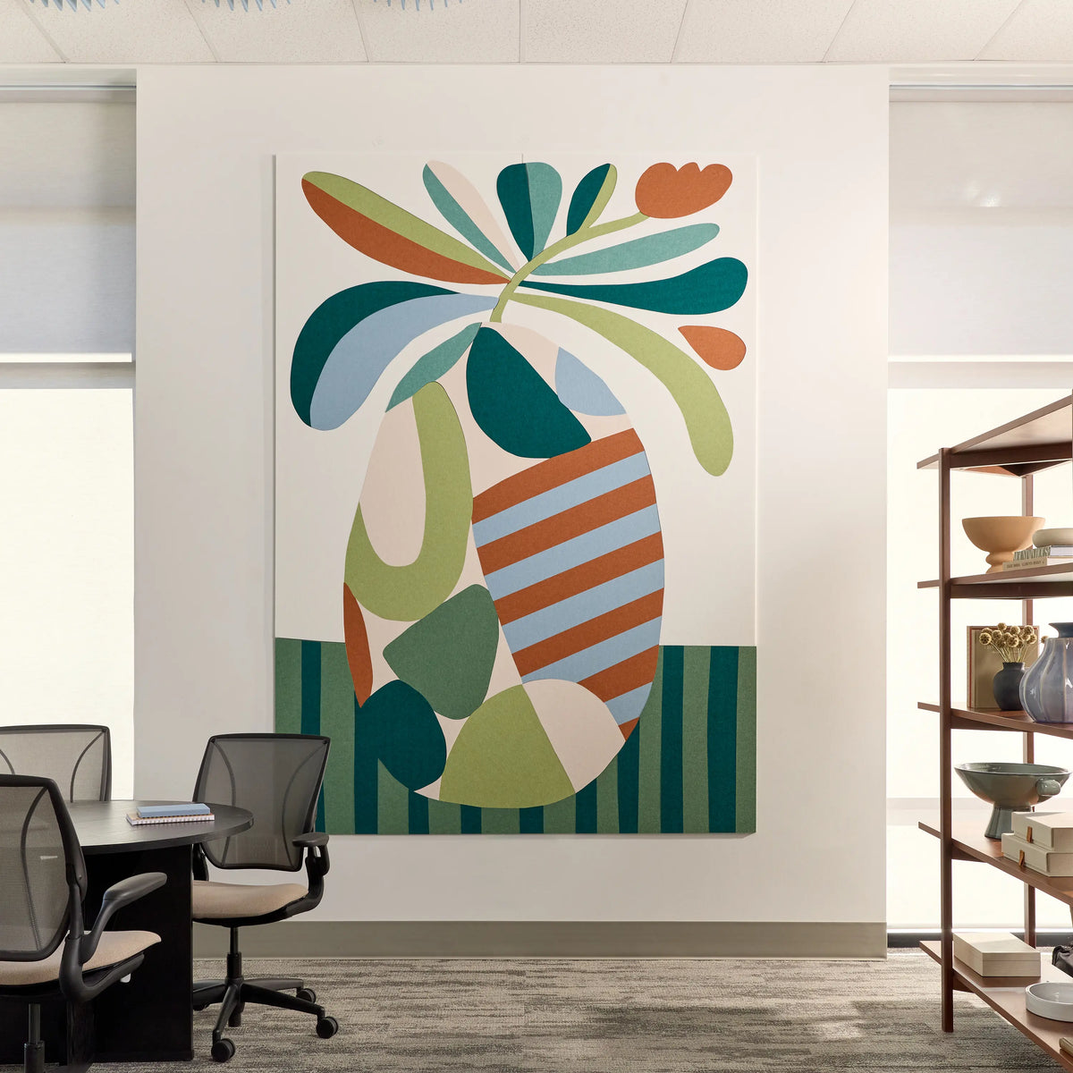 Large abstract acoustic wall art that is installed on a white office wall above a meeting table. The artwork features bold, organic shapes in teal, green, orange, cream, and light blue, with striped and solid patterns.