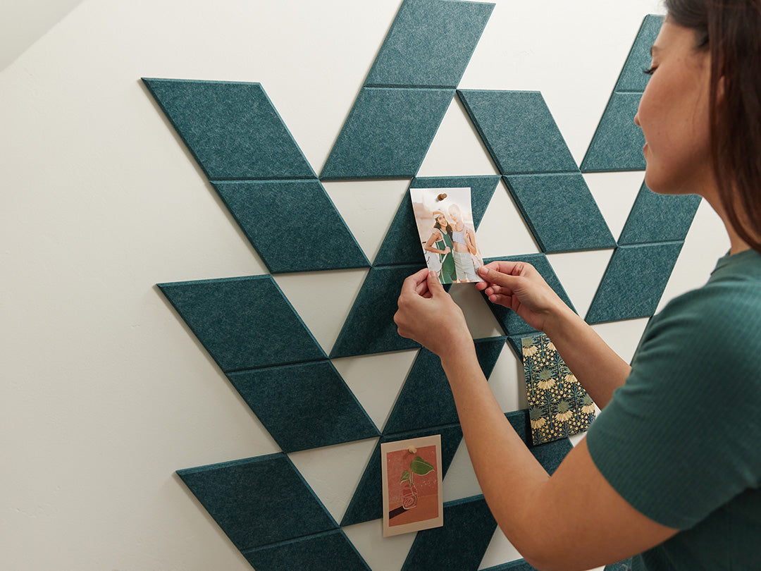 Felt Right tiles in a shade of teal with a woman pinning pictures on the tiles