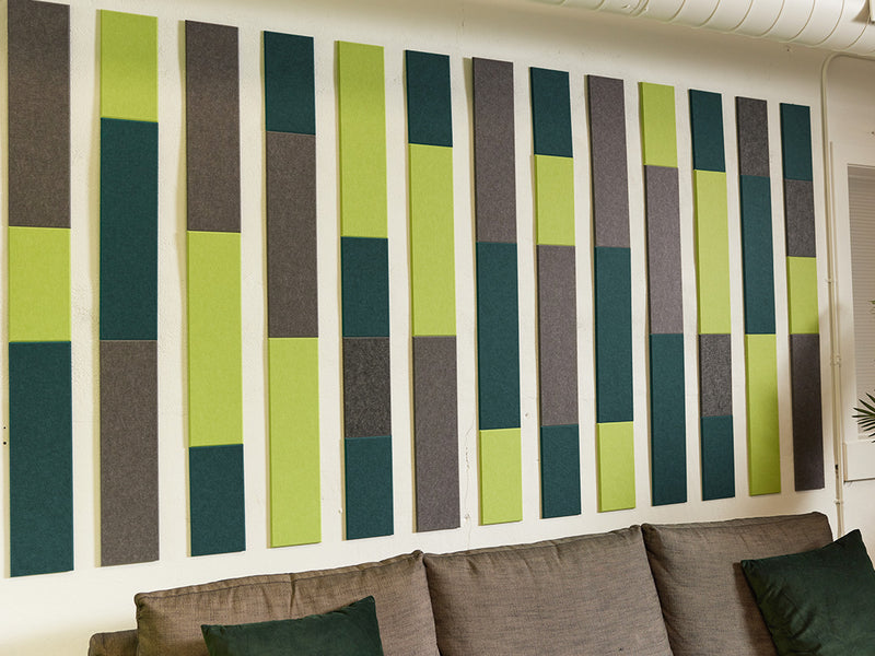 A Felt Right wall art design in shades of grey and green above a couch on the wall in a stripe like pattern 