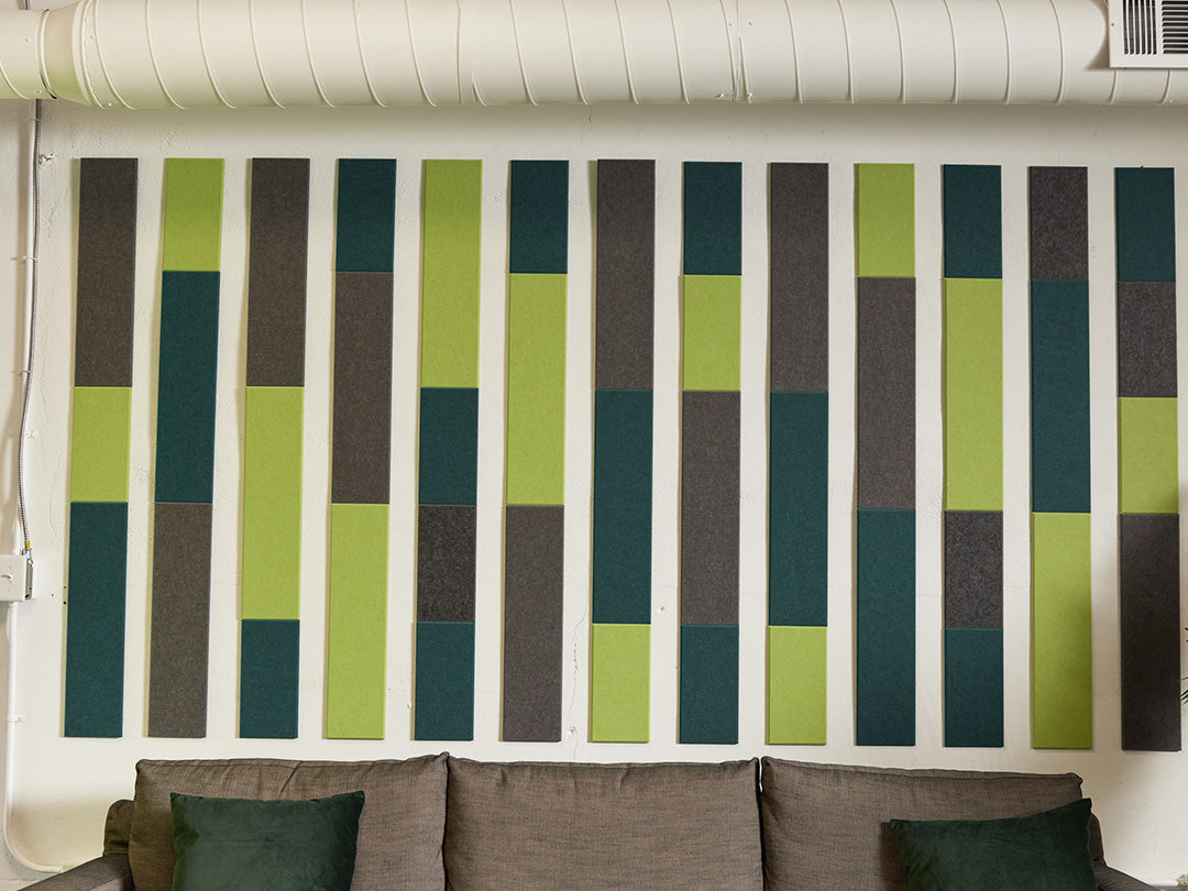 A Felt Right wall art design in shades of grey and green above a couch on the wall in a stripe like pattern 