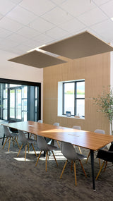 Two charcoal gray square acoustic panels suspended from white ceiling grid above conference table.