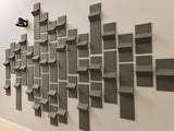 Gray three-dimensional tiles mounted on wall in staggered pattern with varied depths and angles.