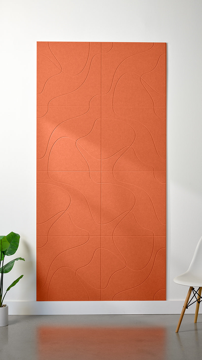 Orange Felt Right 4’ x 8’ PET felt panel with flowing lines similar to a topographical map engraved into the material against a white wall. A plant and chair are in the foreground.
