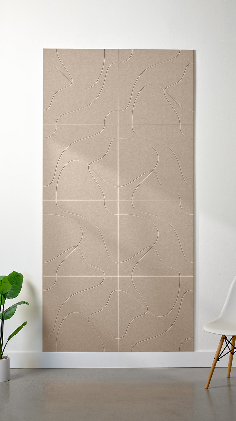 Camel Felt Right 4’ x 8’ PET felt panel with flowing lines similar to a topographical map engraved into the material against a white wall. A plant and chair are in the foreground.