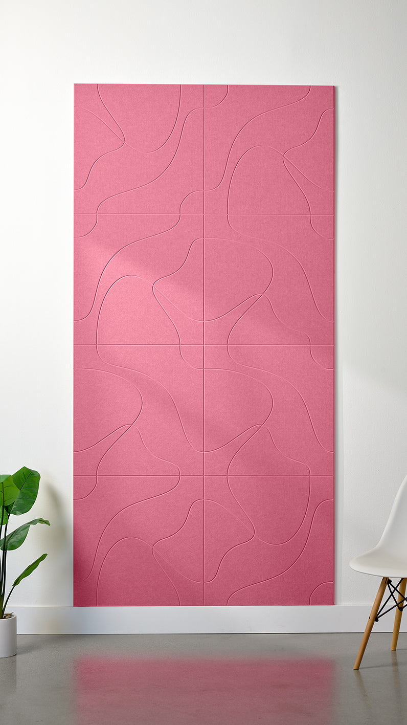 Hot pink Felt Right 4’ x 8’ PET felt panel with flowing lines similar to a topographical map engraved into the material against a white wall. A plant and chair are in the foreground.