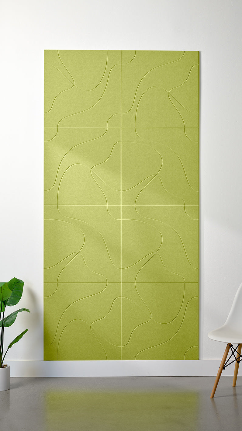 Bright green Felt Right 4’ x 8’ PET felt panel with flowing lines similar to a topographical map engraved into the material against a white wall. A plant and chair are in the foreground.
