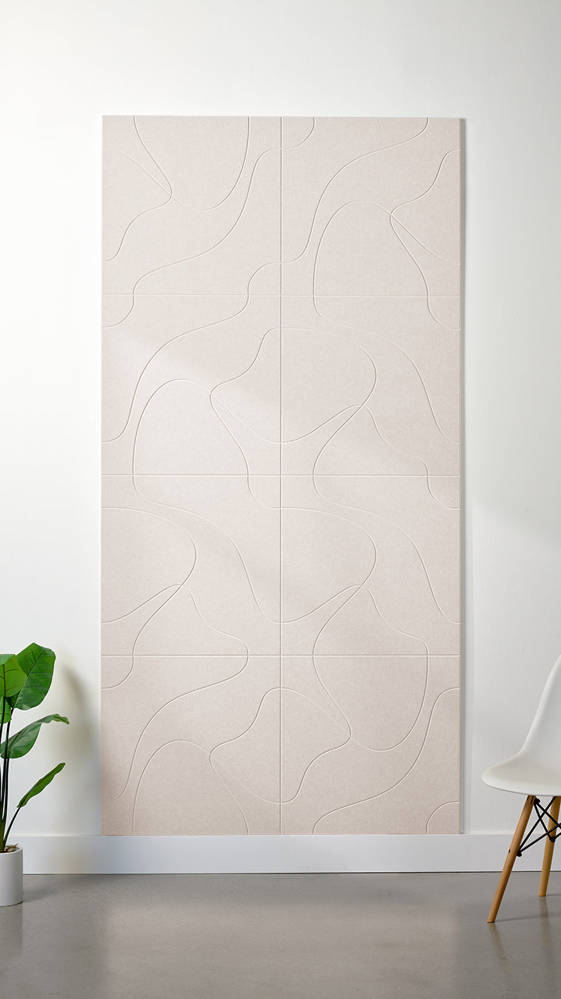 Heathered beige Felt Right 4’ x 8’ PET felt panel with flowing lines similar to a topographical map engraved into the material against a white wall. A plant and chair are in the foreground.