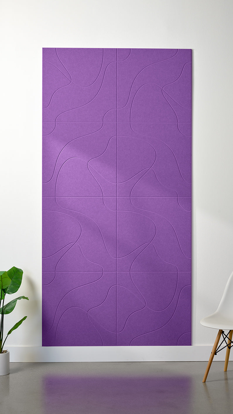 Lavender Felt Right 4’ x 8’ PET felt panel with flowing lines similar to a topographical map engraved into the material against a white wall. A plant and chair are in the foreground.