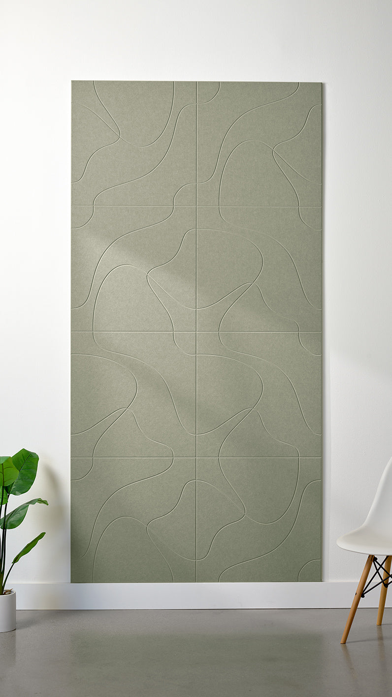 Sage green Felt Right 4’ x 8’ PET felt panel with flowing lines similar to a topographical map engraved into the material against a white wall. A plant and chair are in the foreground.