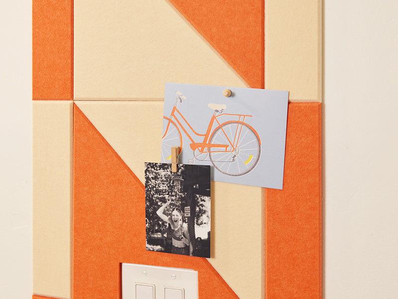 Felt Right tiles in shades of orange and cream in a twist pattern on the wall with cards and photos pinned on to the felt tiles