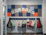 Felt Right wall art design for a classroom above the coat and backpack rack in shades of grey, blue, and orange square tiles that art pinable with a welcome sign.