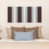 Striped wall art above a bed with decorative pillows